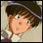 Pixelated anime-style character with brown hair and green eyes, wearing a dark cap with a purple stripe, against a light background with text reading "AnimeIM" and "com" on black.