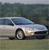 Pixelated image of a light-colored sedan in motion on a road with blurred background.