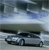 Pixelated static image of a silver sedan on a road under a cloudy sky with blue and gray tones.
