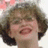 A pixelated image of a person with short brown hair and glasses, smiling widely against a light background.