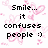 Pixelated black text reads "Smile... it confuses people :)" over a white background with pink pixel art flowers and hearts.