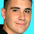 Pixelated close-up of a person's face with short dark hair against a solid light blue background, displayed as a static 50x50 buddy icon.