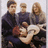 Pixelated group photo of four people with a person in the foreground making a hand gesture, next to pink text on black background reading 'I love Fall Out Boy so so so so so much'