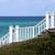 Pixelated coastal scene with white railing, blue water, and green terrain under light blue sky.