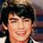 Pixelated static image of a person with dark hair and a light-colored top, smiling with visible teeth against a blurred background.