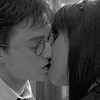 Black-and-white close-up of two people in a kiss, one wearing round glasses and a collared shirt with a tie, the other with long dark hair.