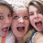 Three people in close proximity with one person's mouth open wide, all faces visible against a light background.