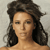 Pixelated portrait of a person with long dark hair against a light gray background, showing a neutral expression.
