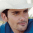 Pixelated close-up of a person wearing a white cap and blue shirt, with visible ear and facial features against a light background.