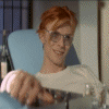 nine shows a person with red hair and glasses in a light blue chair, wearing a white shirt, with a glass of water and a bottle in the background, and a teal with text