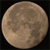 A circular, pixelated image of a full moon with visible crater patterns against a black background.