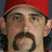 A pixelated image of a person wearing a red cap, with visible facial hair and dark curly hair beneath the cap.