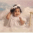 Pixelated image of a person with dark hair tied back, wearing a white top, holding a light-colored object against a soft pastel background.
