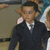 A person in a dark suit and white shirt appears in a of four with slight variations in background and pose