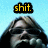 Pixelated image with yellow text 'shit.' on black background above a blurred figure against light blue backdrop.