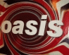 A static image shows the word 'oasis' in white lowercase letters on a red and white spiral background.