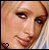 Pixelated close-up of a person's face with light brown hair and dark eyes, featuring a small heart symbol in the bottom-left corner on a transparent background.