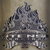 Pixelated static image of a gray, textured object resembling a rock or mineral cluster with white highlights on a muted brown background.
