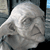 Pixelated grayscale image of a stylized animal head with closed eyes and rounded ears against a dark background.