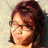 Pixelated close-up of a person with dark curly hair, wearing glasses and light-colored clothing against a gradient background.