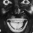 Pixelated grayscale image of a stylized face with large eyes and a wide open mouth, rendered in a low-resolution, blocky style.