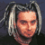 Pixelated static image of a person's face with light-colored hair against dark background, rendered in low-resolution style typical of early 2000s digital art.