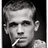 Black-and-white pixelated image of a person with short hair holding a cigarette, next to a camera icon and the text 'Cam' on black background.