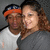 Two people pose together in a pixelated image with a gray background; the right person wears a dark gray top and the left person wears a white top with an orange and blue headband.