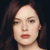 Pixelated close-up of a person with dark hair, light skin, and red lips against a dark background.