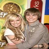 Two people embrace in a close-up pose with a colorful background featuring partial text and symbols.