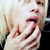 A person with light-colored hair covers their mouth with their hand in a sequence of showing subtle movement