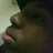 A pixelated close-up of a dark-skinned figure with closed eyes, pink lips, and a light-colored background, rendered in low-resolution style.