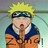 Pixelated character with spiky yellow hair, dark headband, blue and orange outfit, mouth open in a shout, standing against a blurred greenish background.