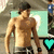 A shirtless man with dark hair and a wristband stands against a light blue background with a heart symbol changing color.
