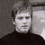 Static grayscale image of a person with short dark hair wearing a dark turtleneck sweater against a muted background.
