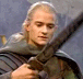 A character with long light hair in a dark cloak holds various weapons and arrows