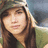 A pixelated image of a person with long brown hair wearing a green cap and shirt, next to a yellow background with '=]' text.