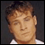 Static pixelated image of a person's face with light brown hair and closed eyes against a dark background, wearing a white shirt.