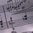 Pixelated grayscale image of a musical staff with scattered black note symbols on light gray background.