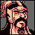Pixelated static icon of a bearded man with long hair wearing glasses, rendered in red and beige tones against a gray background.
