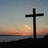 A static image shows a dark cross on a beach at sunset with purple text reading "I've done a lot of things wrong but I swear I'm a BELIEVER".