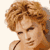 Static pixelated image of a person with curly light brown hair, visible facial features including eyes and nose, and partial shoulder/neck area against a plain background.