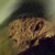 Pixelated static image of a brown furry animal-like figure with dark eyes and nose against a blurred greenish background, likely from an old digital animation or game asset.