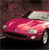 A red car with a white roof is positioned at an angle against a dark background, showing front and side details.
