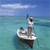 Pixelated image of a small boat on calm water under a blue sky with faint clouds.