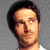 Static pixelated portrait of a person with dark hair and light skin against gray background, cropped to show head and upper neck.