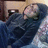 Pixelated image of a person in dark clothing lying on a light surface with a blurred background.