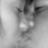 Grayscale pixelated image of a figure with dark hair and light eyes, partially obscured by low resolution.