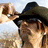 A pixelated image of a person wearing a dark hat and sunglasses, with text overlays on a red background.