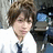 A pixelated static image shows a person with brown hair wearing a white shirt and dark tie, holding a black camera with blue screen against a blurred background.